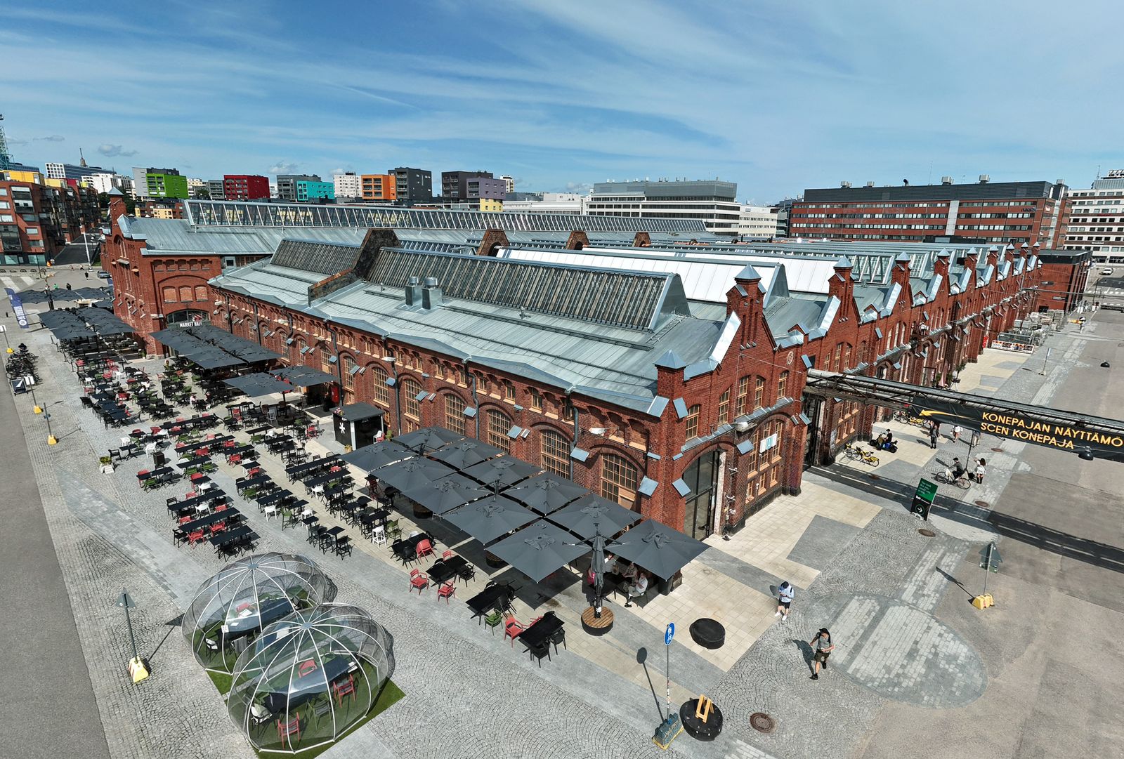 The red-brick Konepaja halls and their yard from above, August 2026
